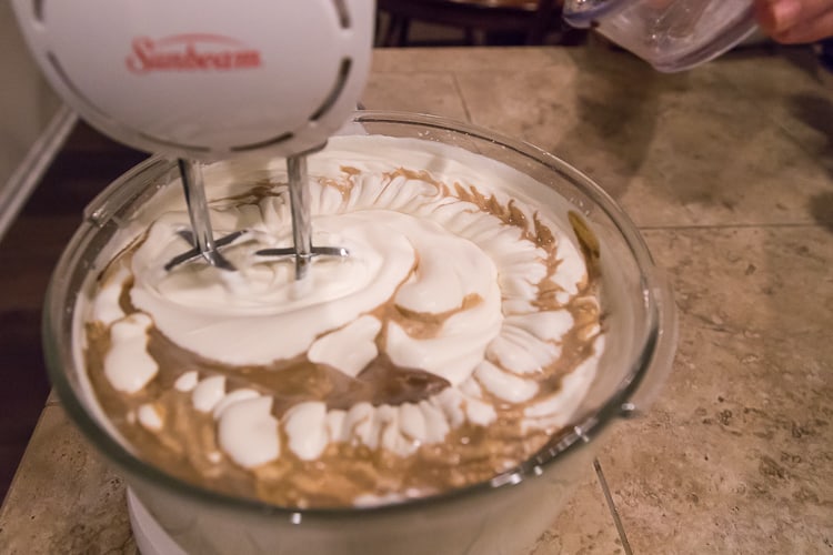 Keep the mixer on low speed and slowly add two teaspoons of vanilla extract to the condensed milk and whipping cream.