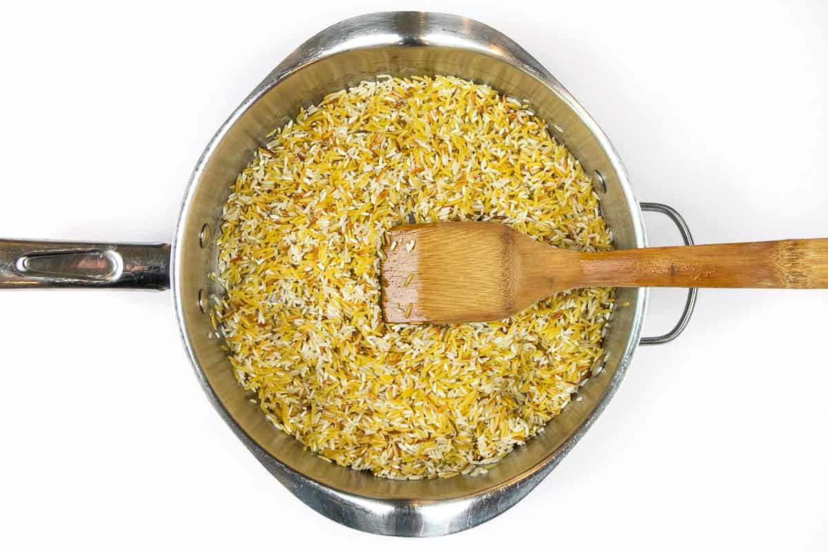 Brown the long-grain rice and orzo pasta in the frying pan.