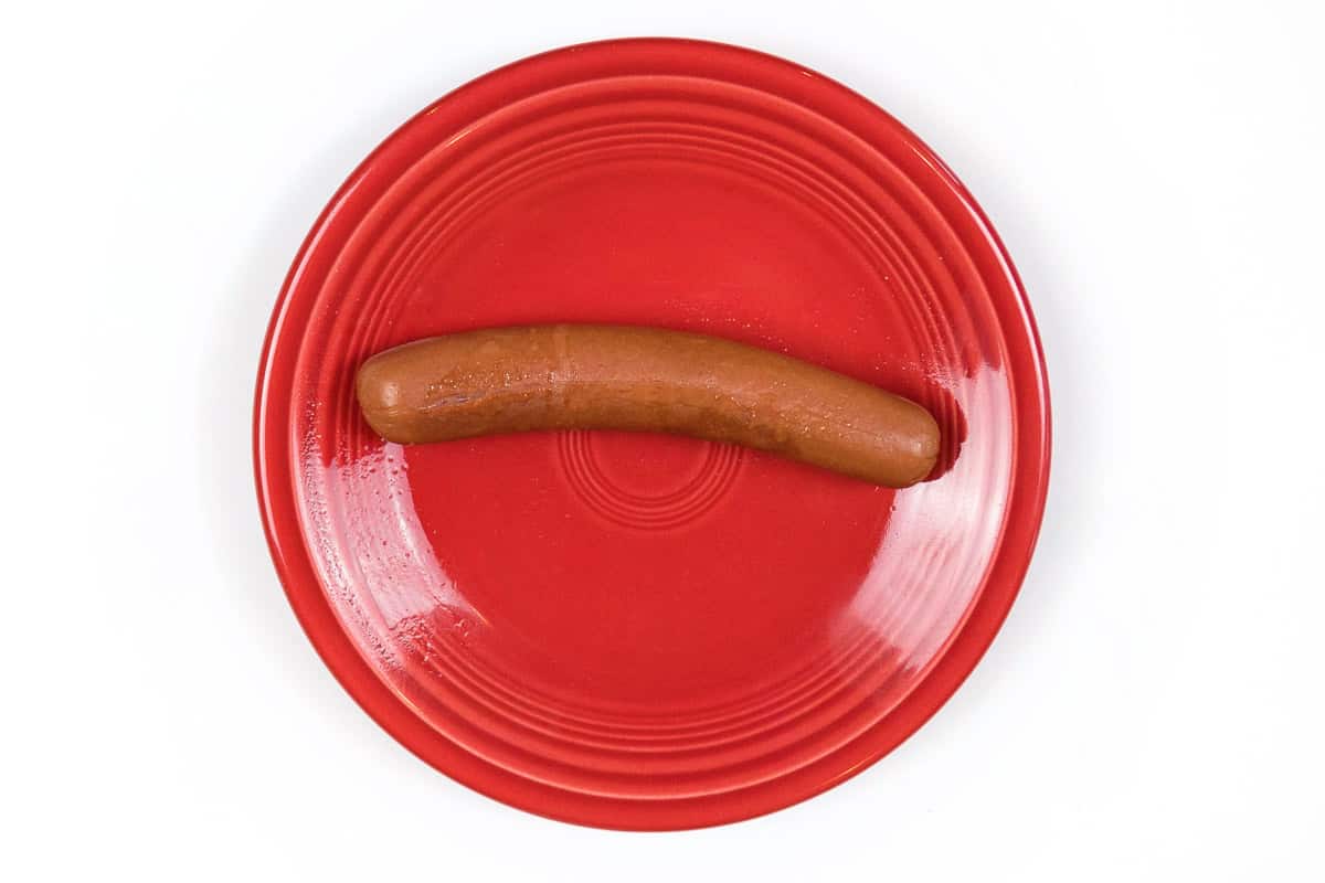A cooked microwaved hot dog on a plate.