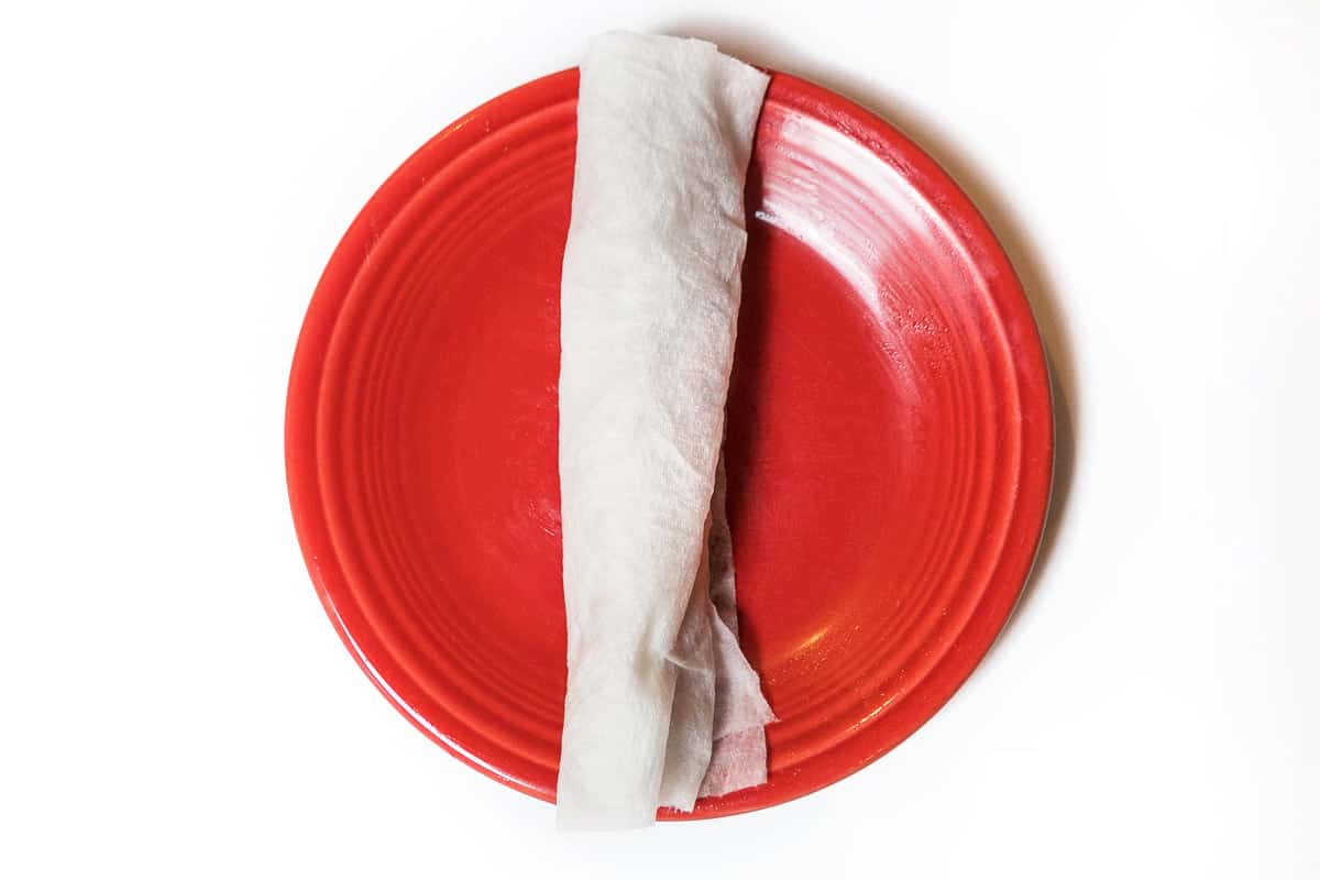 A frozen hot dog in a damp paper towel.