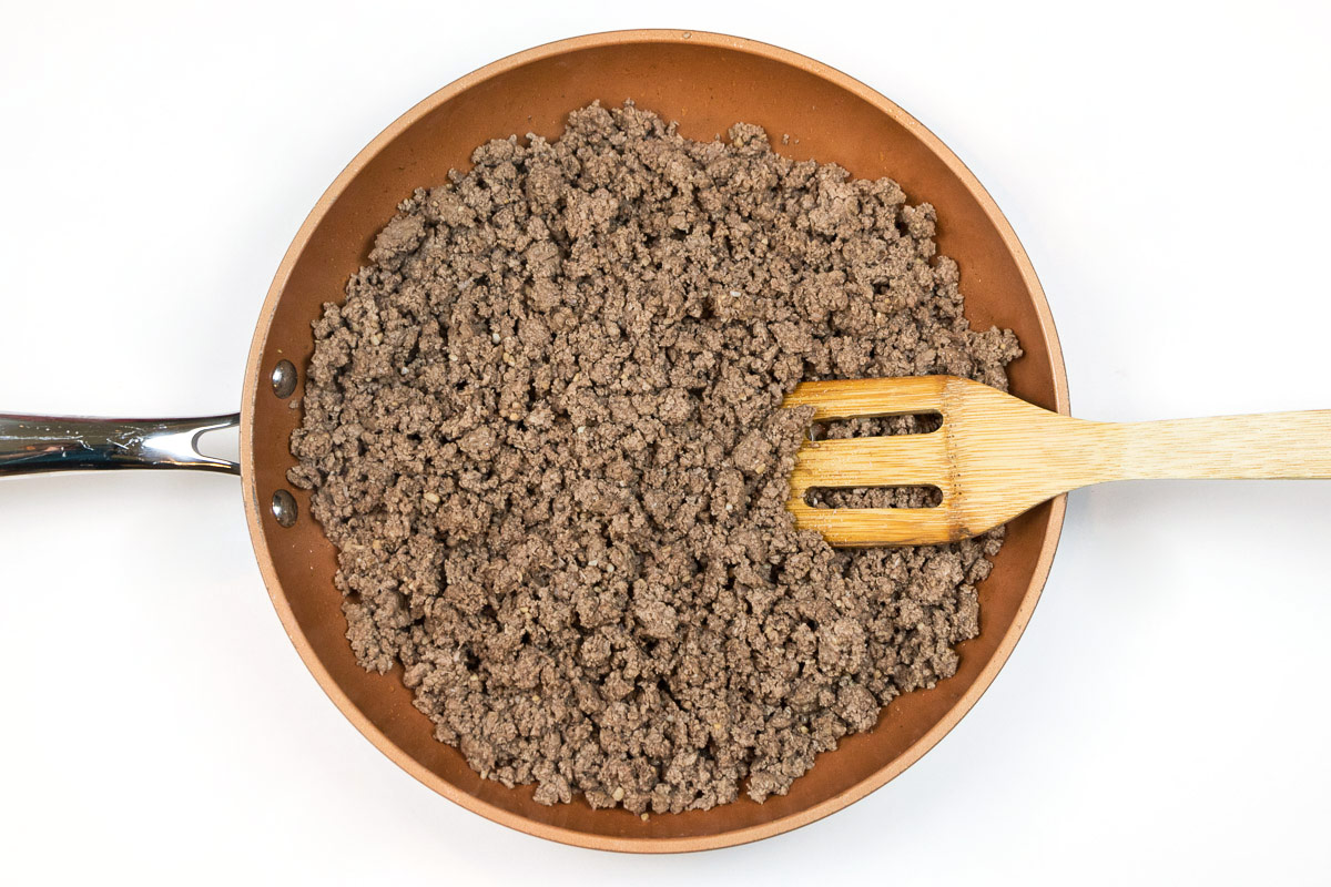 Ground beef and garlic browning in a skillet.