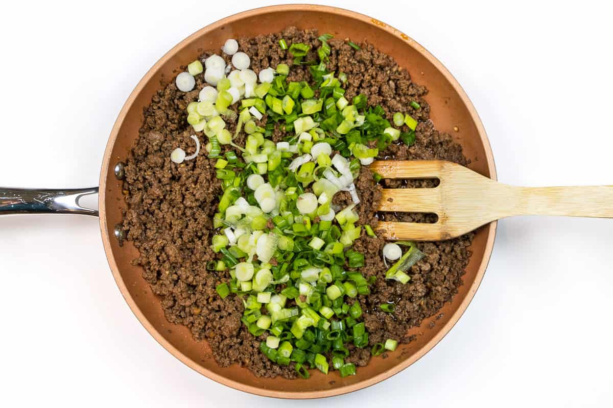 Add the sliced green onions to the ground beef mixture.