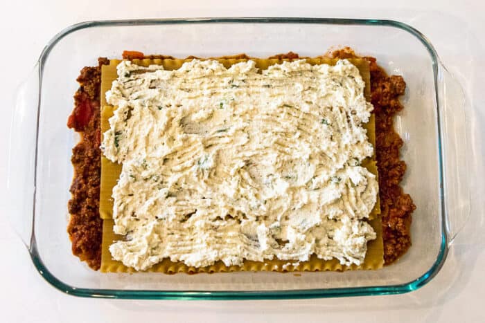 A layer of the parmesan cheese, ricotta cheese, oregano, and basil  over the top of the lasagna noodles.
