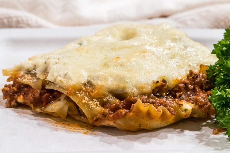 A slice of homemade ricotta cheese lasagna on a plate.