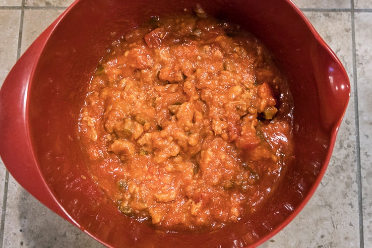 Hot salsa and medium salsa mixed with refried beans in a bowl.