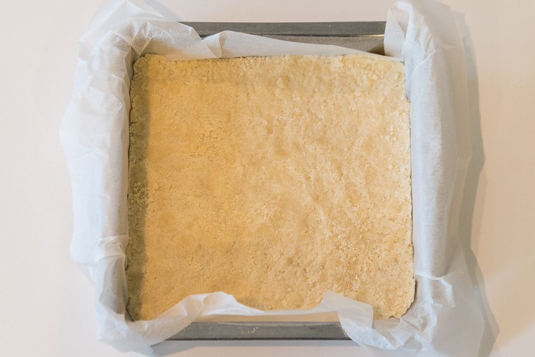 Parchment paper placed in baking pan with lemon bars crust.