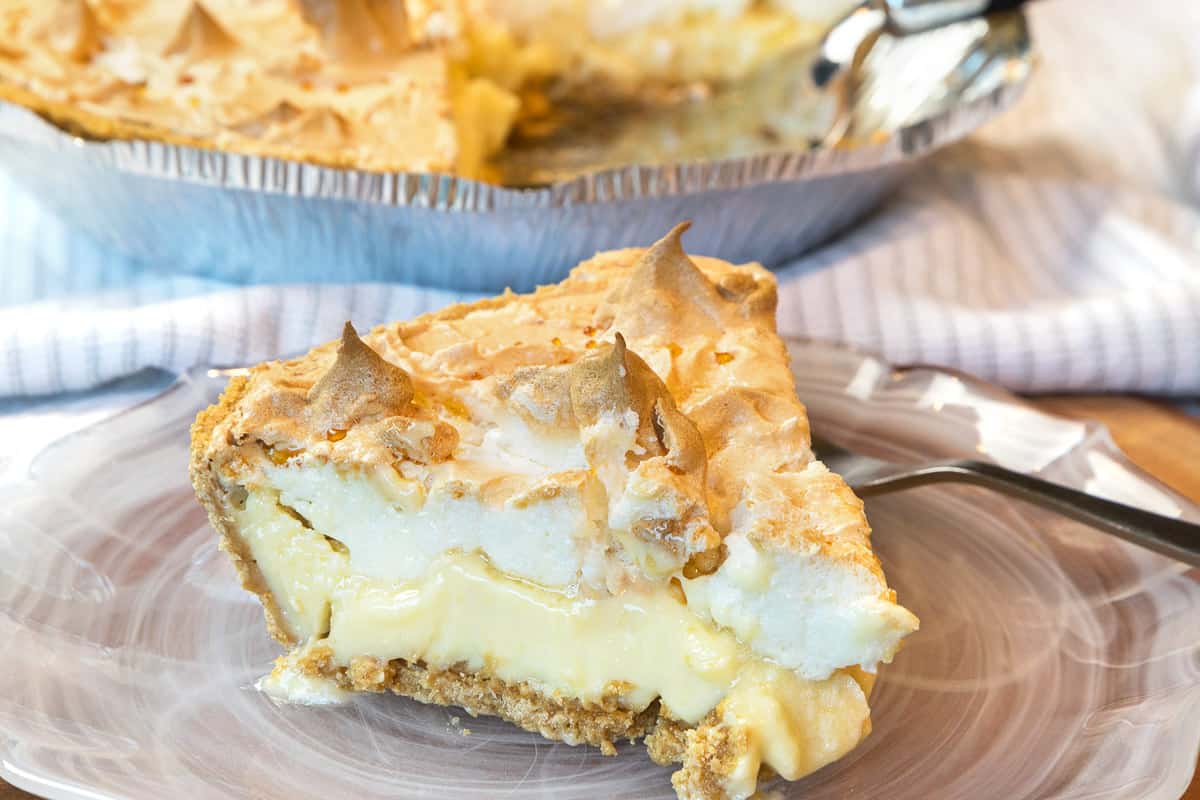 A slice of lemon meringue pie with condensed milk on a plate.