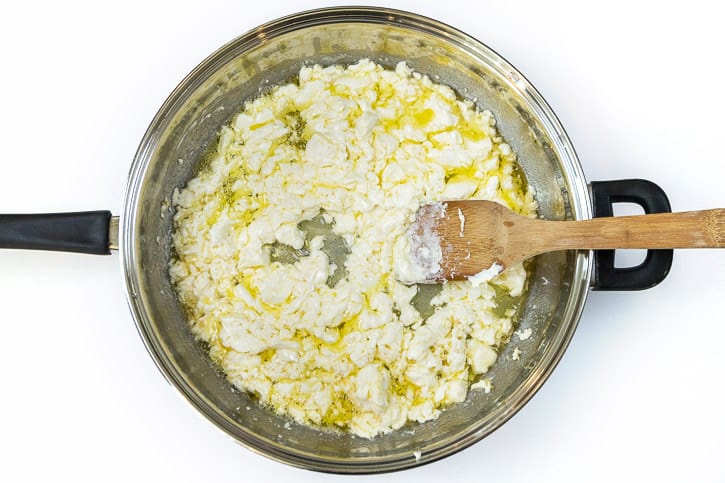 The cream cheese is added to the melted butter and minced garlic in the frying pan.