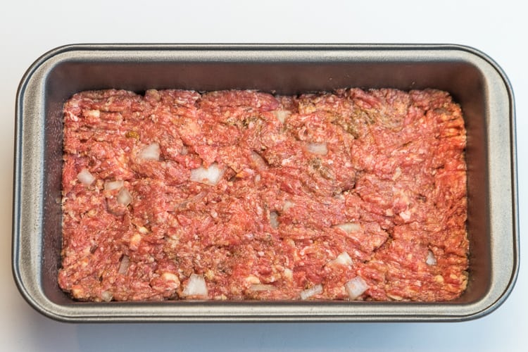 Unbaked beef meatloaf in a loaf pan.