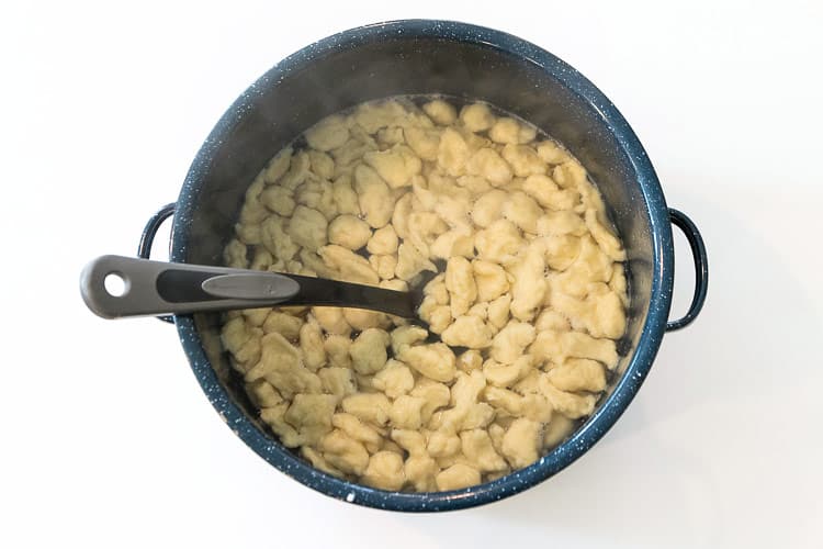 Cooked dumplings in a soup pot.