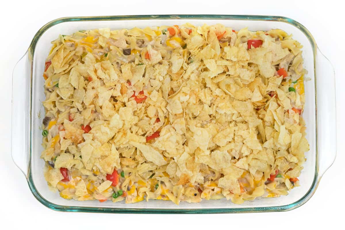 Crushed potato chips are put on top of the tuna noodle casserole.