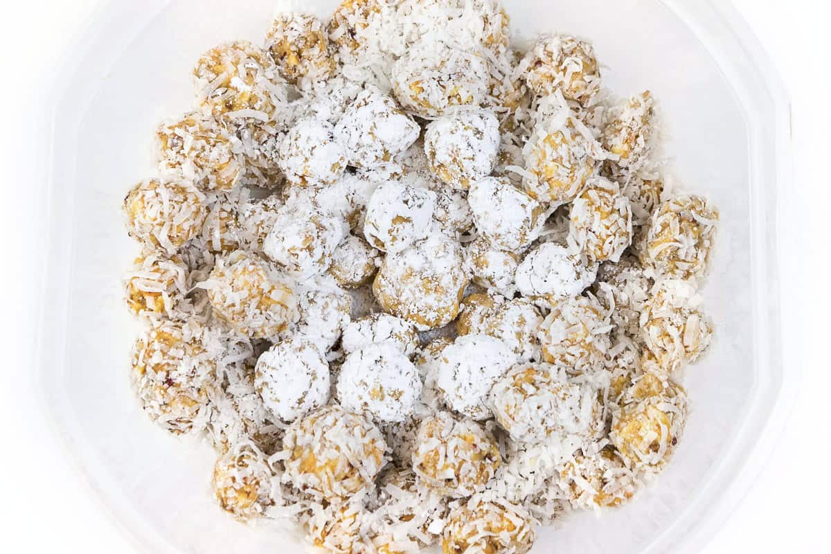 Some orange balls with coconut flakes and some with powdered sugar.