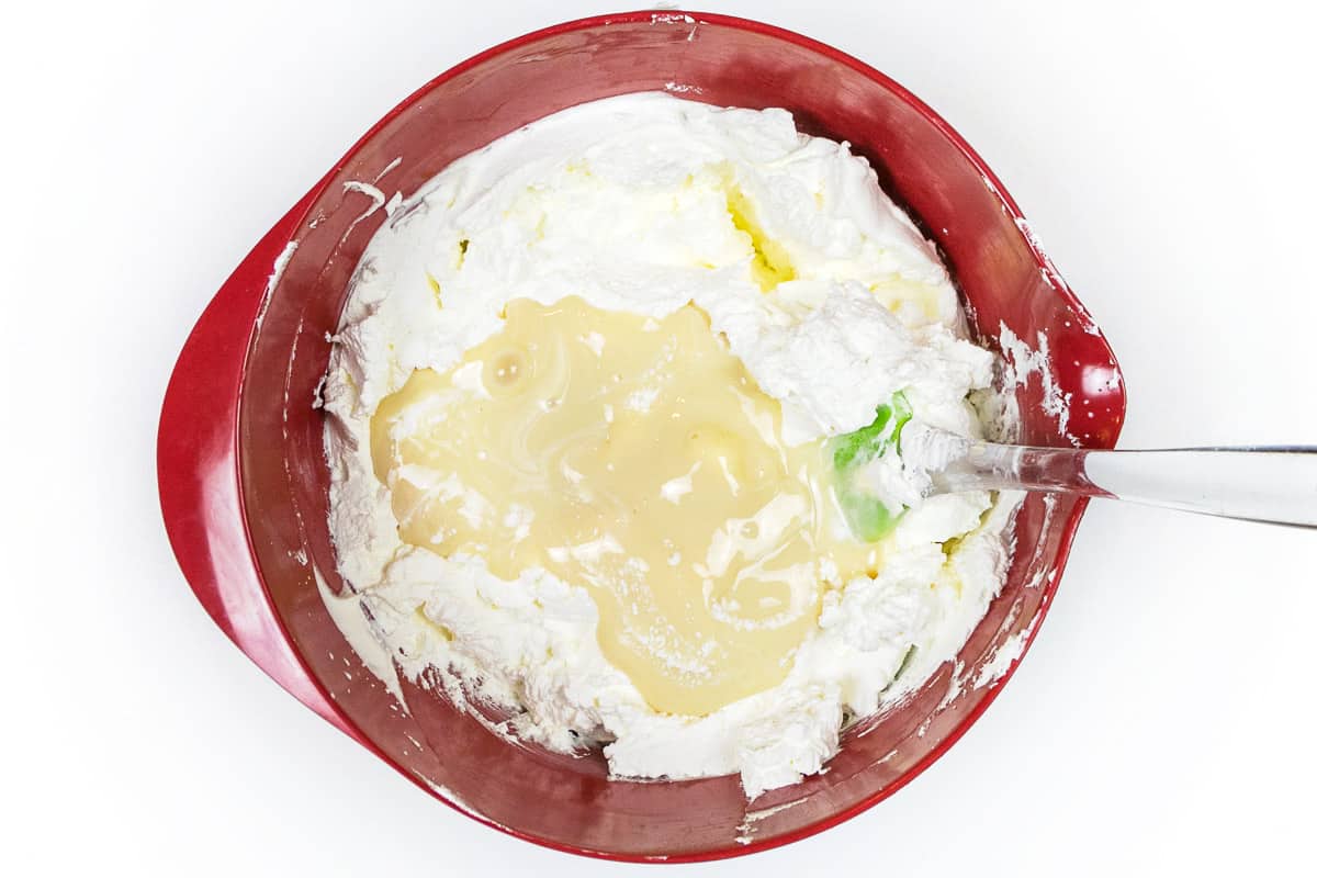 Sweetened condensed milk is added to the heavy whipped cream.