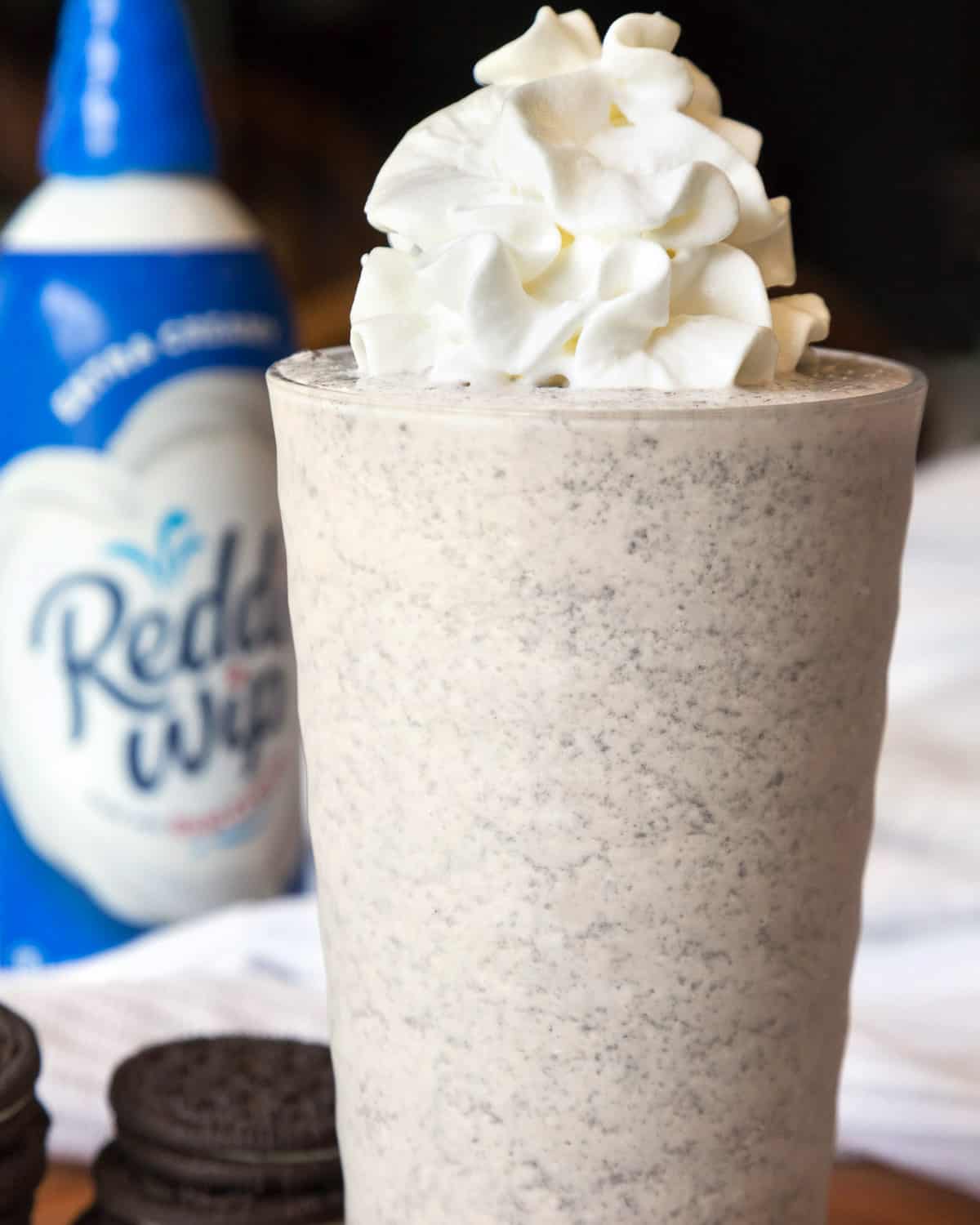 Oreo milkshake recipe with vanilla extract in a cup and topped with whipped cream.