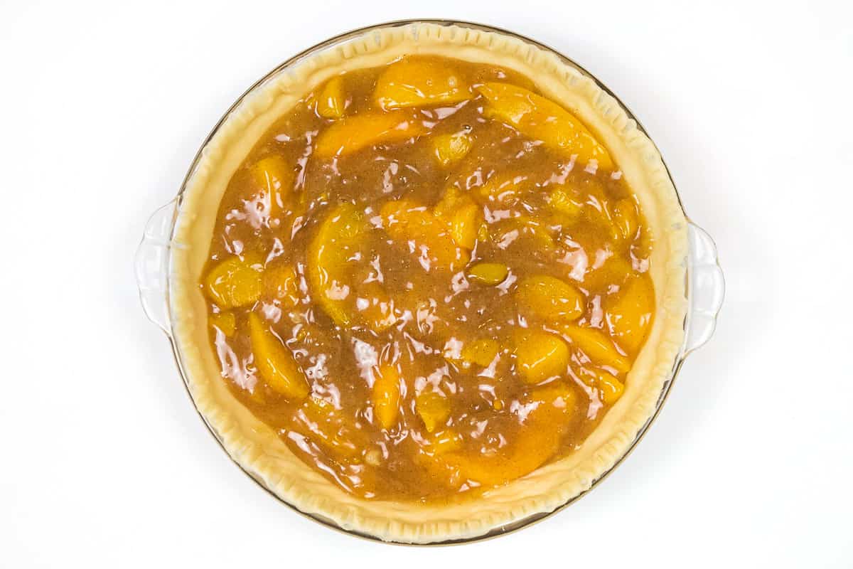Pour the thickened peach juice and peaches into the pie crust.