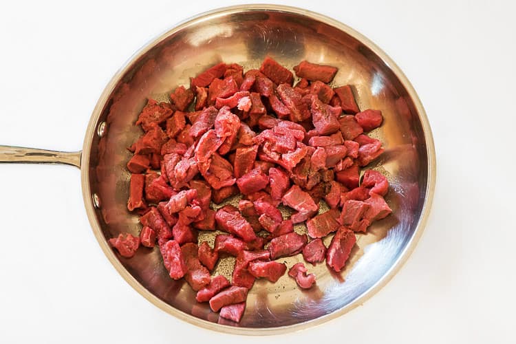 Olive oil and steak in a frying pan.