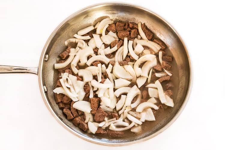 Steal and onions in a frying pan.