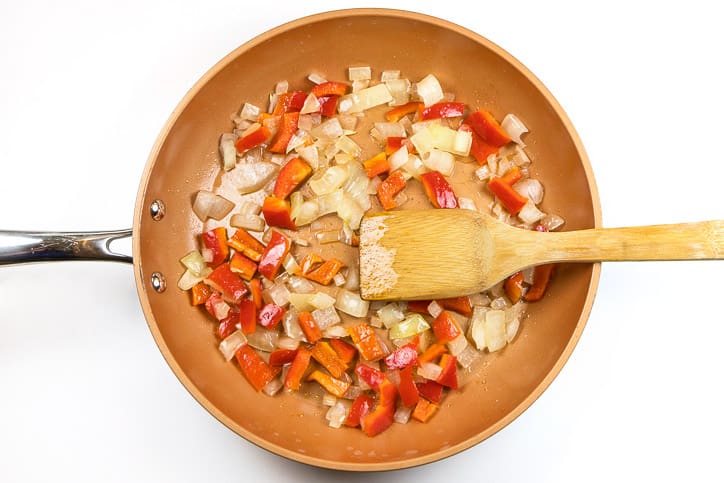 Sauté the onions and red bell peppers in a frying pan for 5 minutes on medium heat.