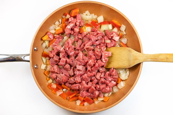 Steak added to the onions and red bell peppers.