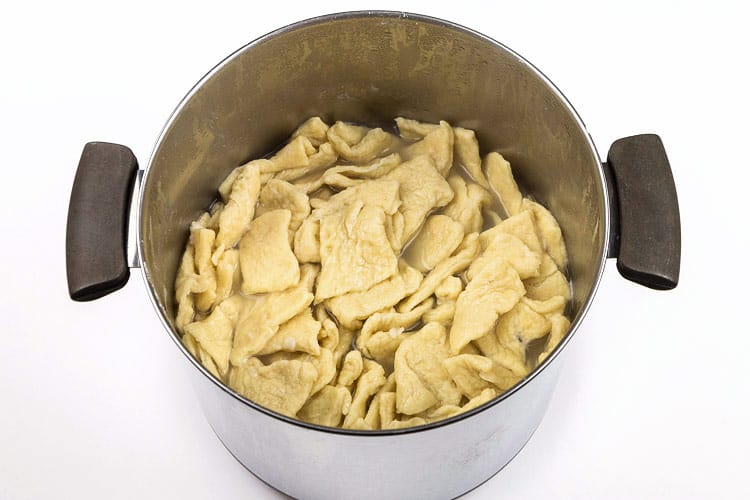 Pierogi dumplings cooking in a pot of water.