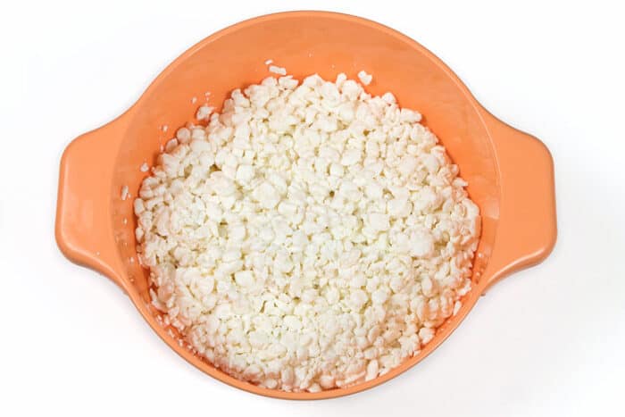 Large curd cottage cheese drained in a colander.