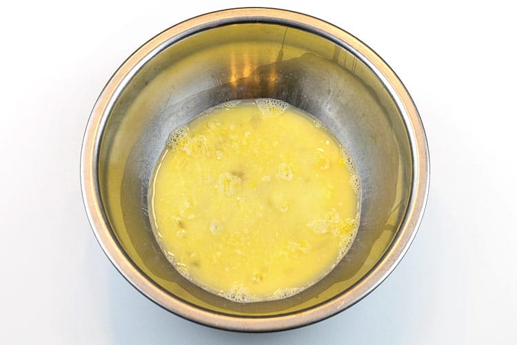 Four beaten eggs and water in a bowl.