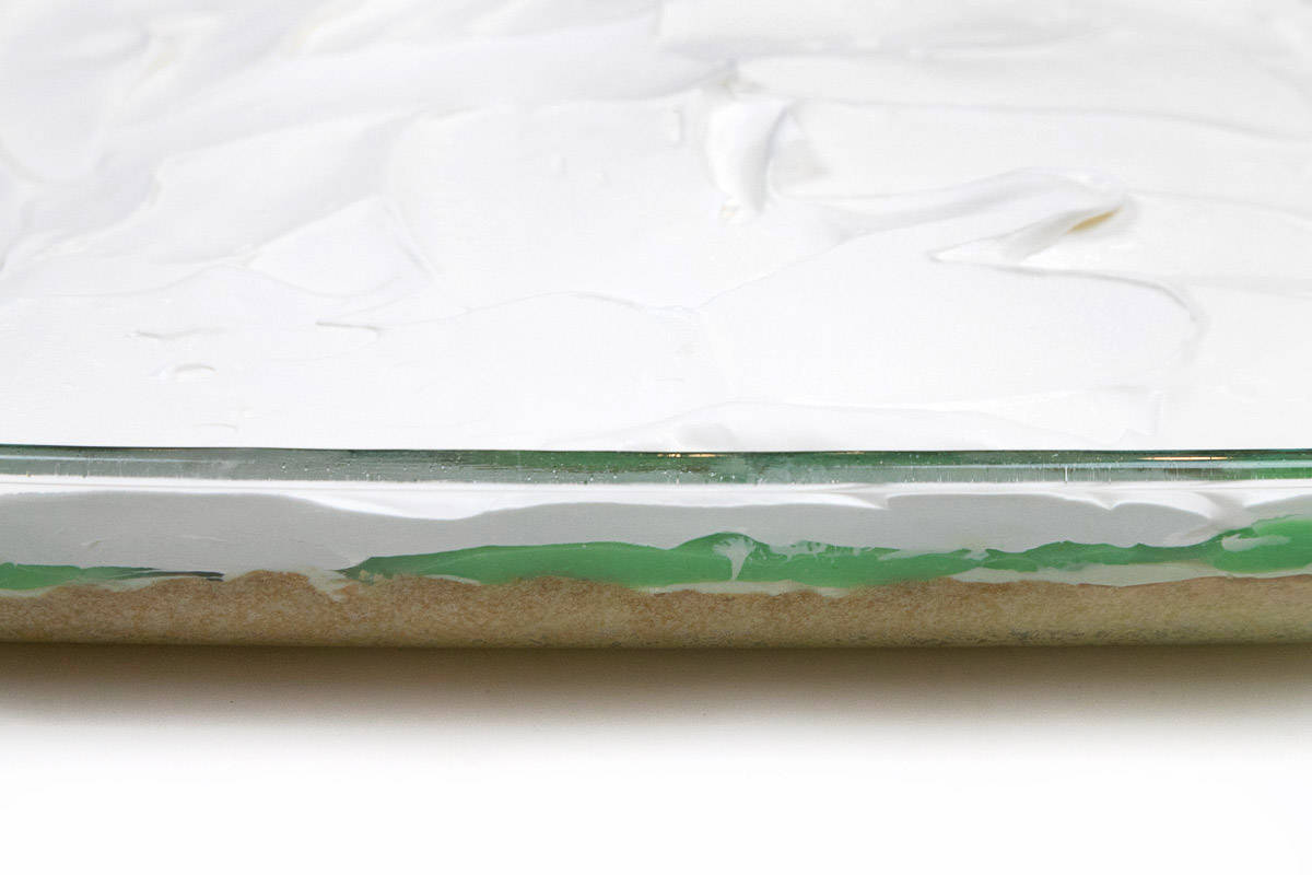 A layered pistachio pudding dessert in a nine by thirteen inch baking dish.