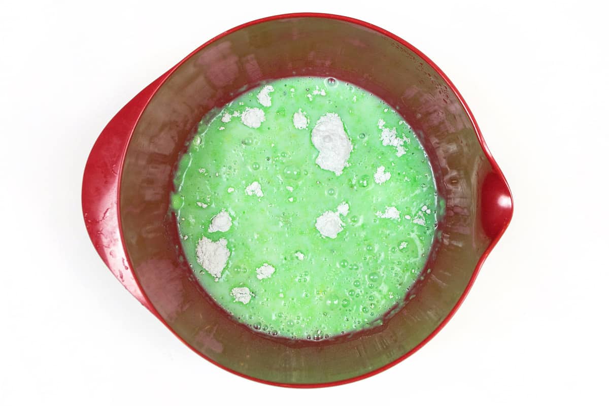 Two packages of instant pistachio pudding and three cups of cold milk in a bowl.