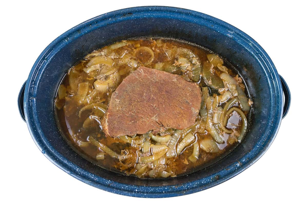 Pot roast in roasting pan with onions.