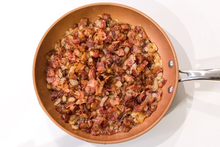 Frying bacon and onions in a frying pan.