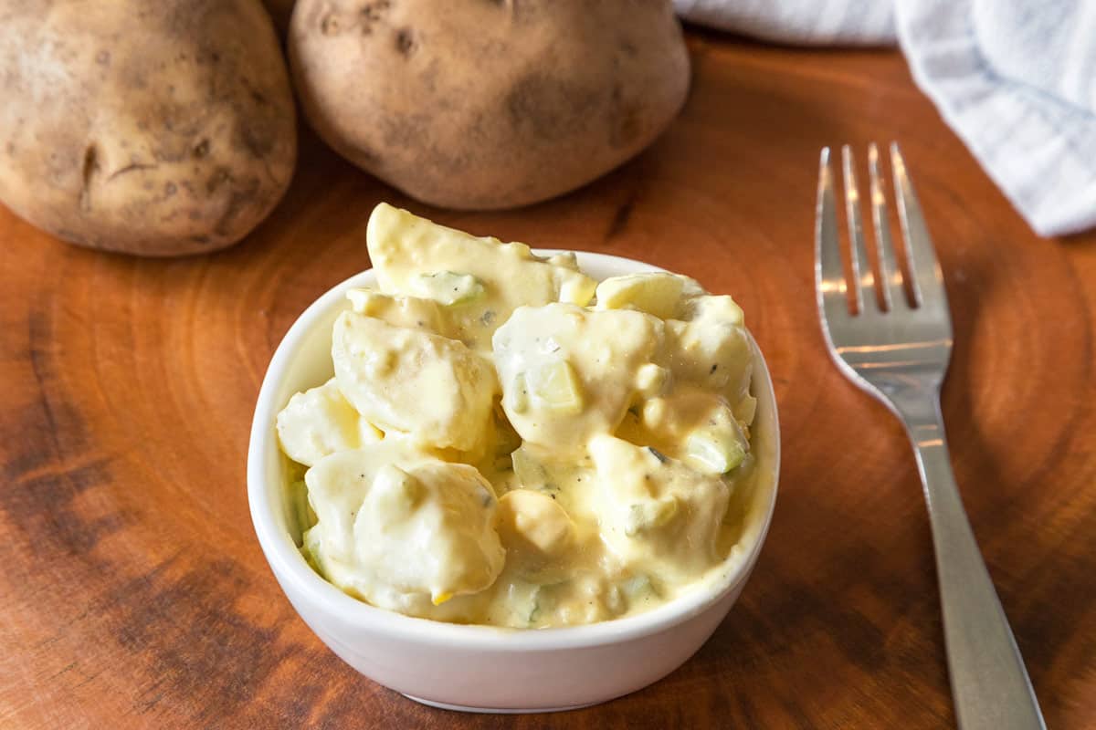 Potato Salad with Eggs and Mustard in a bowl with a fork beside it.