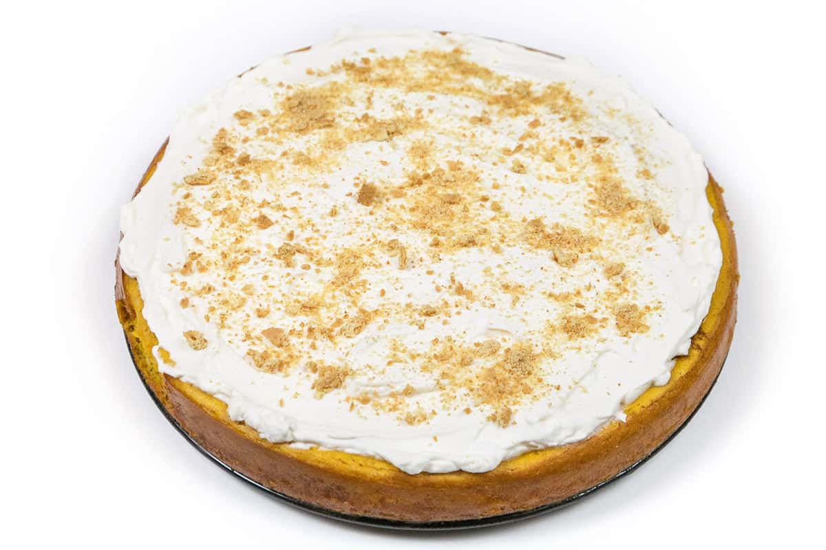 Pumpkin cheesecake with whipped cream and graham cracker crumbs on top.
