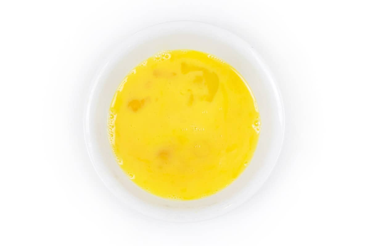 Two large eggs are lightly beaten in a bowl.