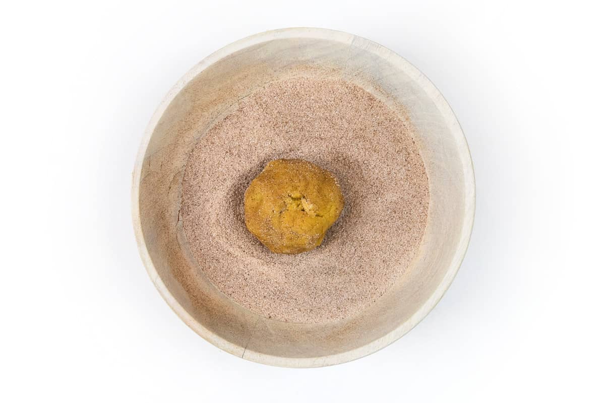 Roll the cookie dough ball into the sugar and cinnamon mixture.