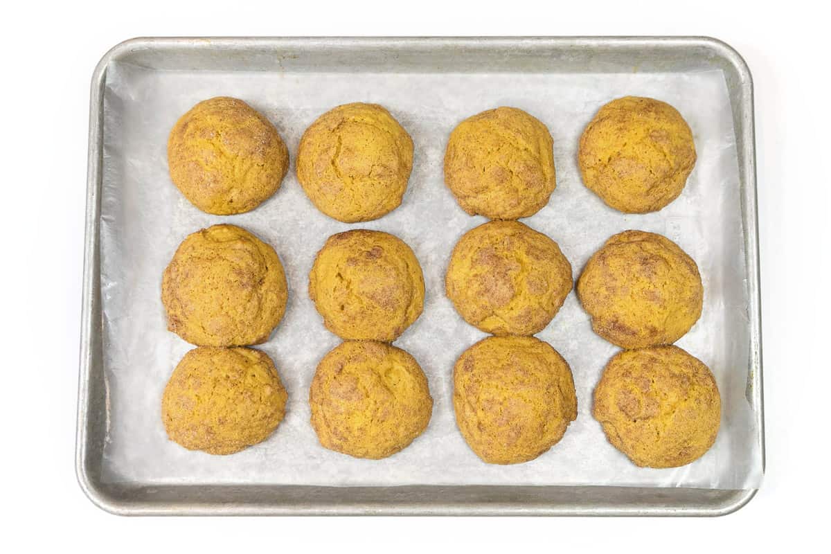 Baked pumpkin snickerdoodle cookies on a cookie sheet.