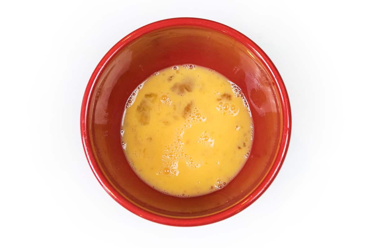 Two large beaten eggs in a bowl.