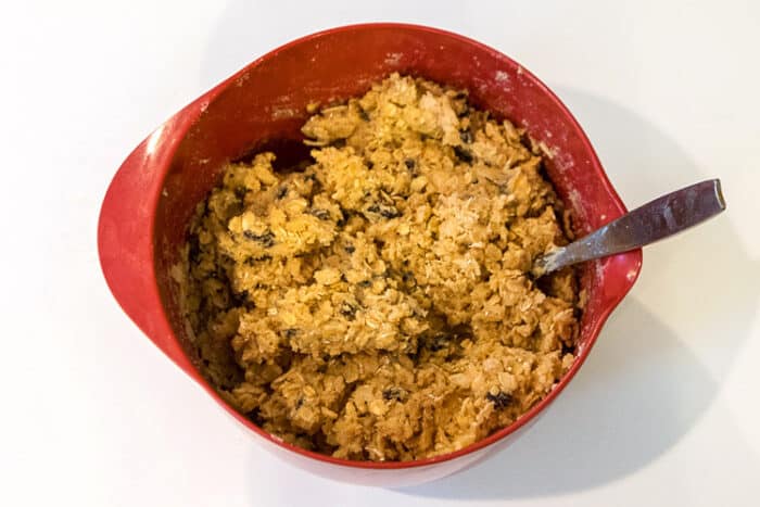 Rice krispies added to raisins, oatmeal, sugar, eggs, brown sugar, butter, vanilla, baking soda, salt, and flour in a bowl.