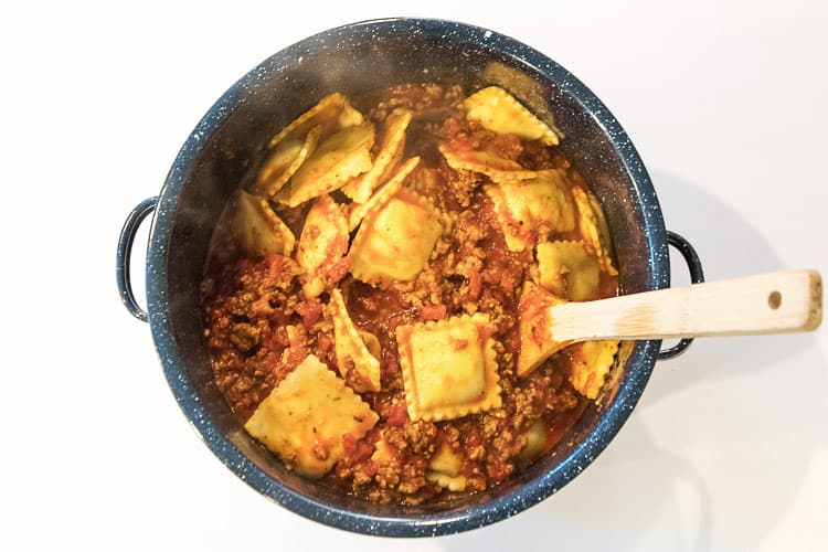 Sausage pasta sauce and five cheese ravioli in a pot.
