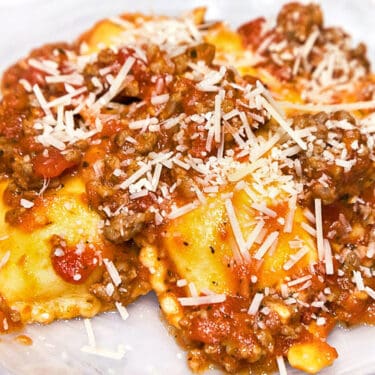 Sausage pasta sauce with five cheese ravioli on a plate.