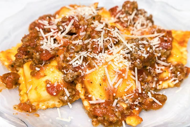 Sausage pasta sauce with five cheese ravioli on a plate.