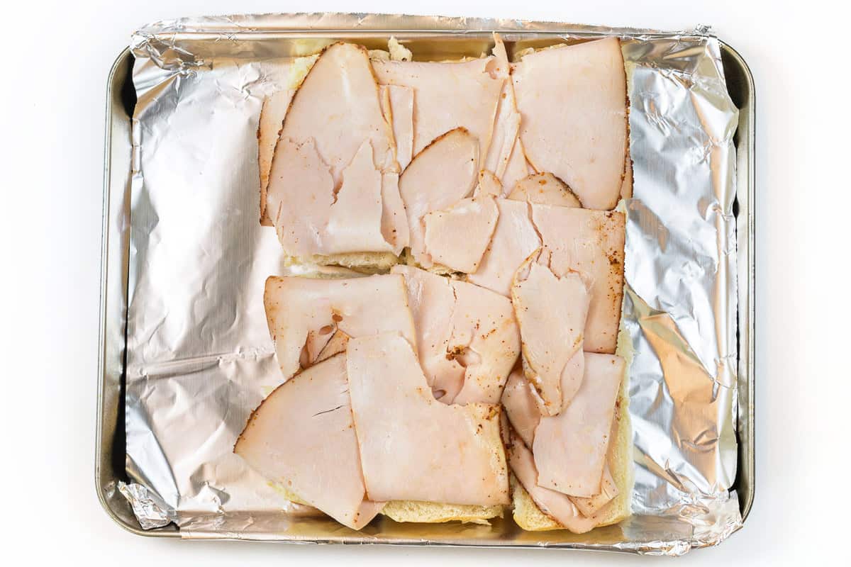 Deli turkey is laid on top of the rolls.