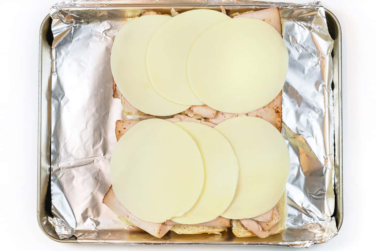 Six slices of Provolone cheese is laid on top of the turkey.