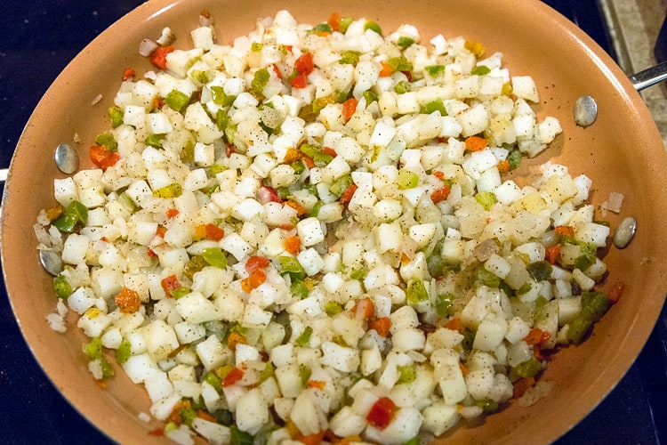Frozen hash browns with onions and peppers in the frying pan.