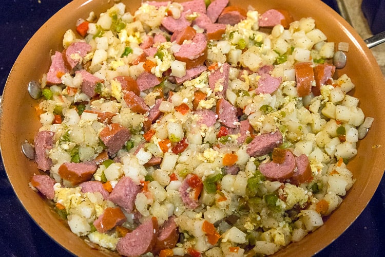 Kielbasa chunks are added to the hash brown mixture.