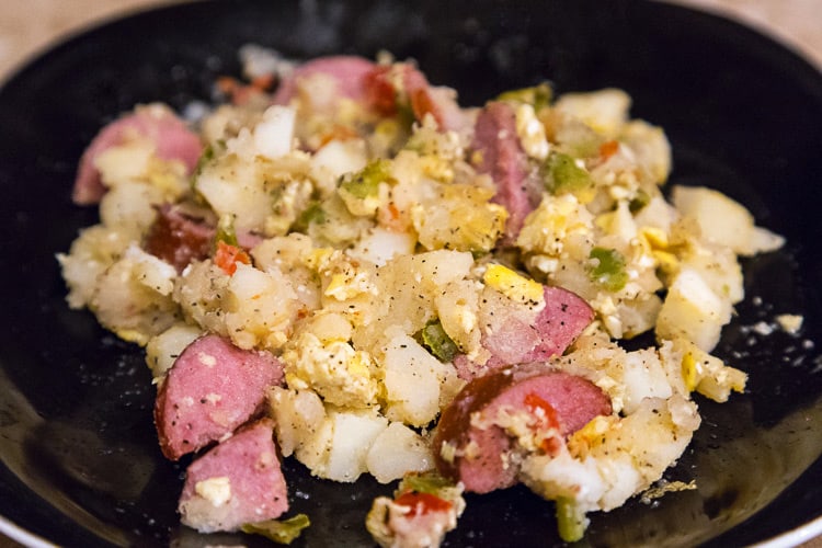 Sausage potato hash with eggs on a plate.
