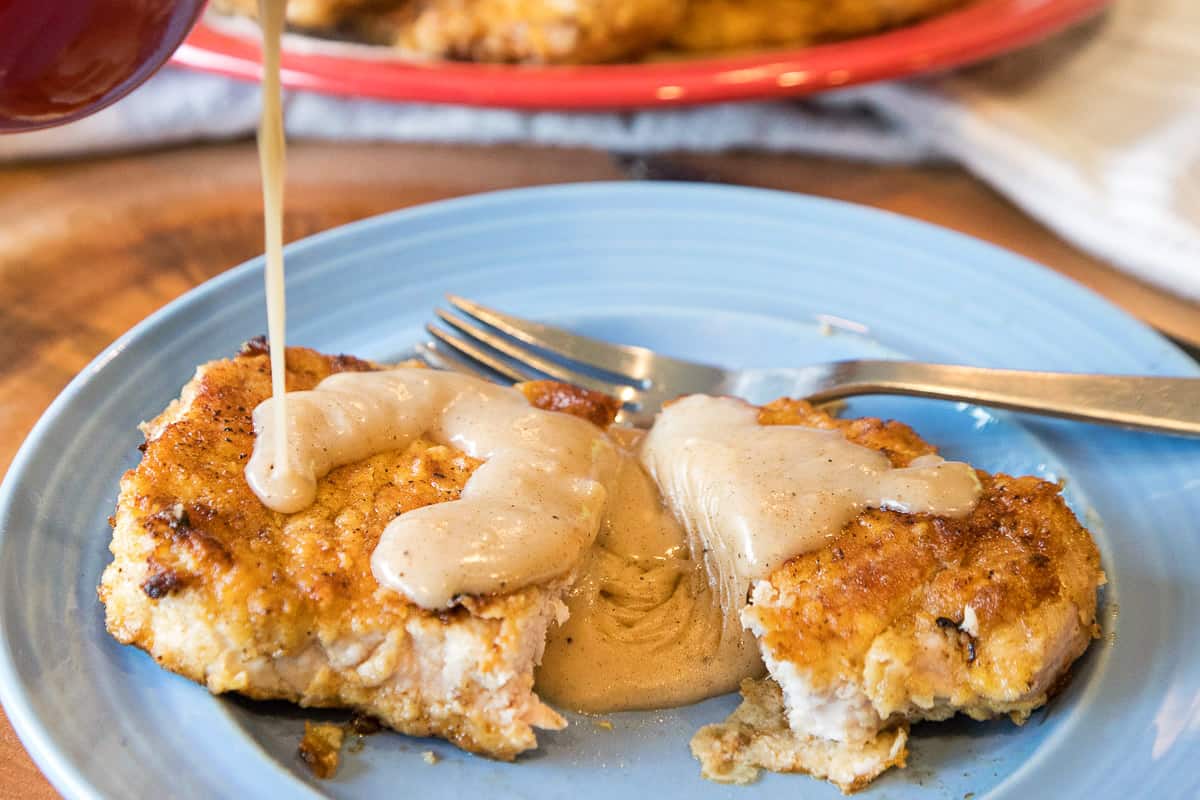 Fried Pork Chops with gravy on a plate.