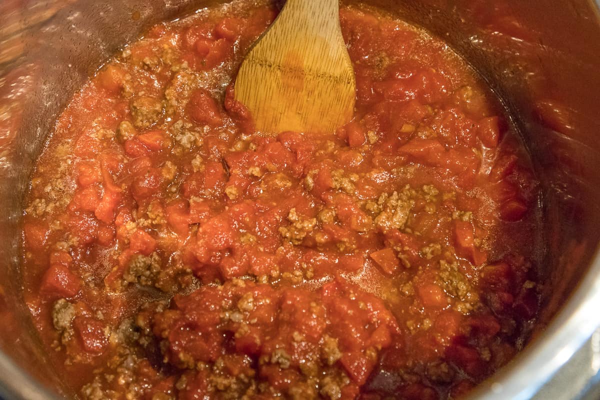 Stir together the browned ground beef, diced tomatoes, tomato paste, and tomato sauce.