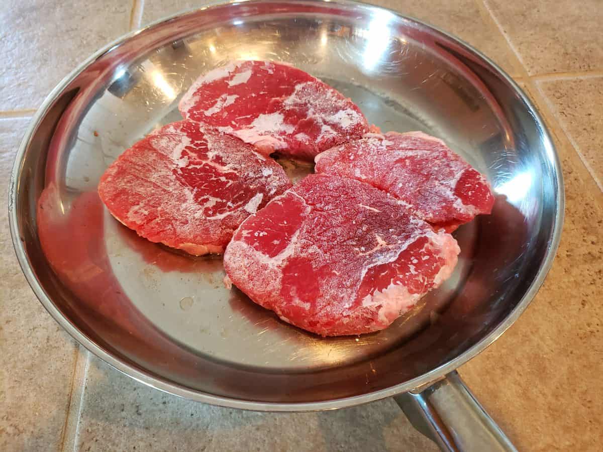 Four  Eye of Round Steak in frying pan.