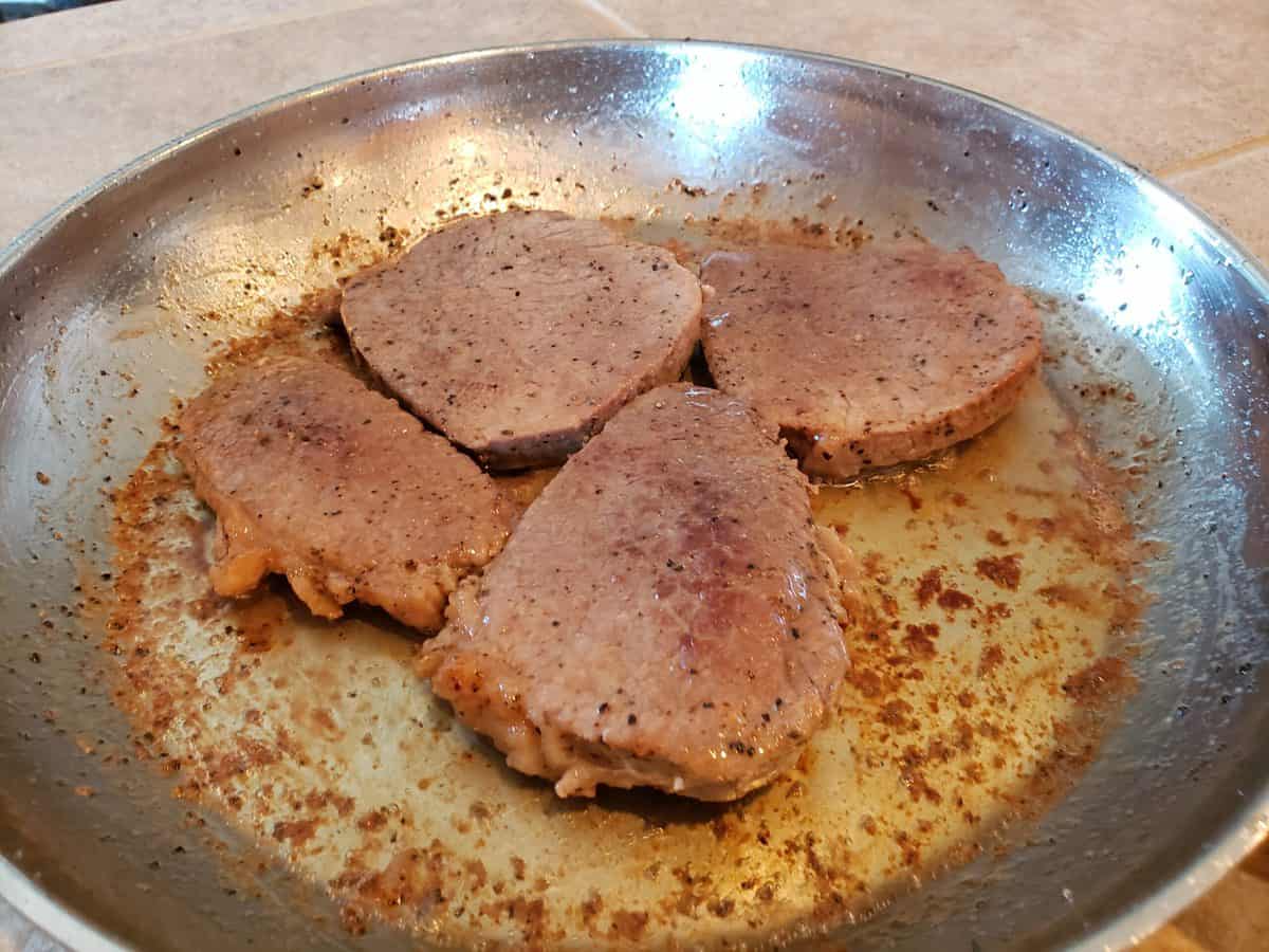 Steaks are done browning in the frying pan.