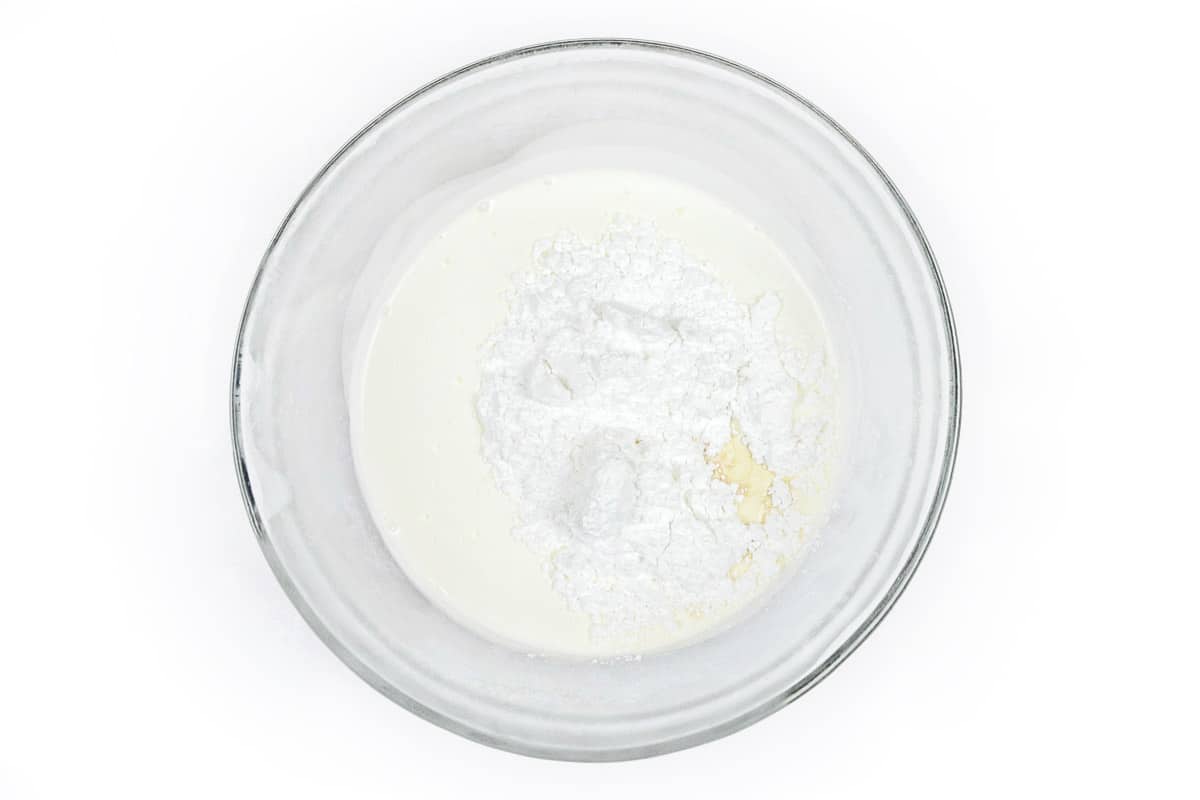 Whipping cream and powdered sugar in a bowl.